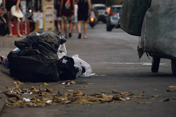 Closeup Pile Rubbish Lies Curb Road People Soft Focus Walking Royalty Free Stock Images