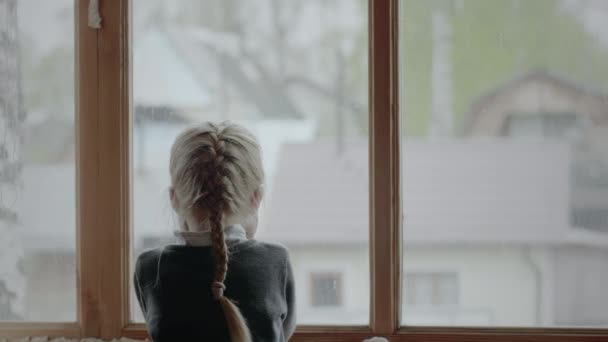En flicka som tittar ut genom fönstret — Stockvideo