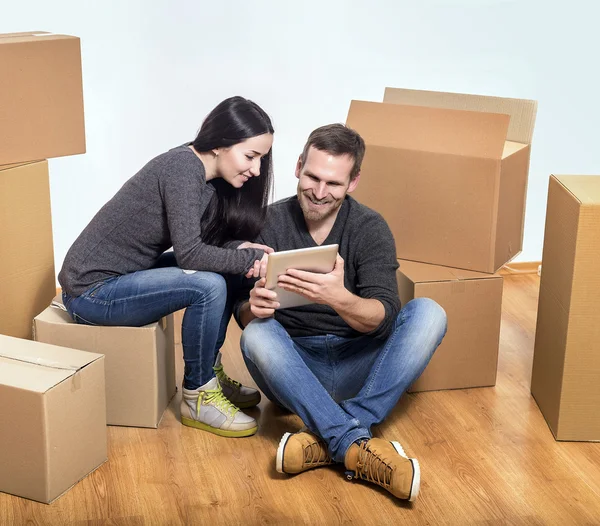 Pareja o amantes sentados en una habitación vacía con cajas de cartón . — Foto de Stock