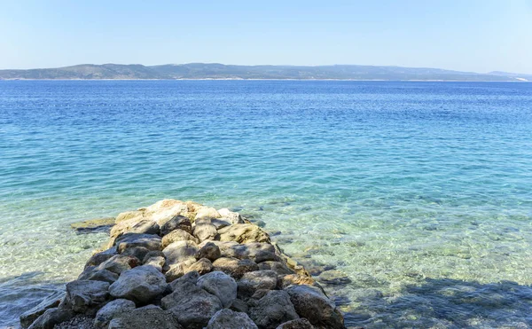 Deniz ve dağ manzarası ufukta.