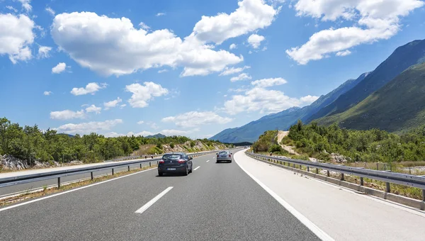 Voitures excès de vitesse sur l'autoroute parmi les paysages de montagne. — Photo