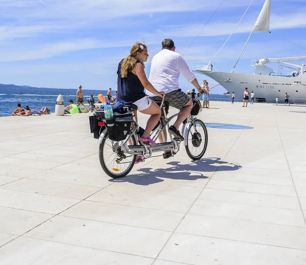 Touristen auf einem Fahrrad-Tandemfahrt entlang des Ufers. — Stockfoto