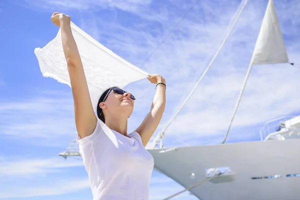 Młoda kobieta trzyma szalik ociera wiatr na wietrze na tle białego statków. — Zdjęcie stockowe