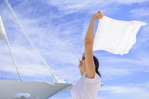 A young woman is holding a wind-scraped scarf in the wind against a white ships background. — Stock Photo, Image