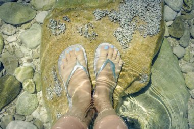 Kadın ayaklarda flip floplar deniz suyu.
