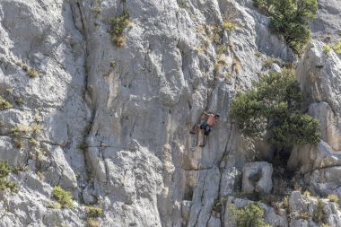 Genç dağcı cliff duvara tırmanıyor.