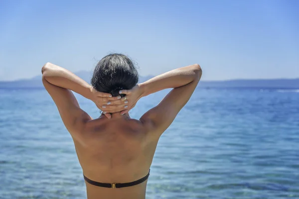 Giovane donna in bikini sulla riva blu del mare . — Foto Stock