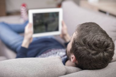 Koltukta oturan bir adam bir tablet Pc kullanır. Arkadan Görünüm.