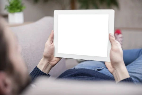 A man sitting on the couch uses a tablet PC. Back view. — Stock Photo, Image