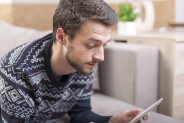 Genç adam kanepede yatan bir tablet bilgisayarda arıyorum.