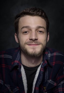 Karanlık bir arka plan üzerinde sakallı genç bir adam portresi.