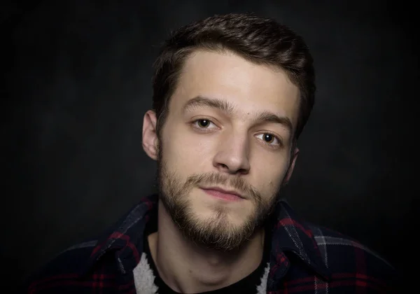 Retrato de un joven con barba sobre fondo oscuro . — Foto de Stock