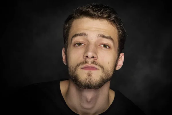 Retrato de un joven con barba sobre fondo oscuro . — Foto de Stock