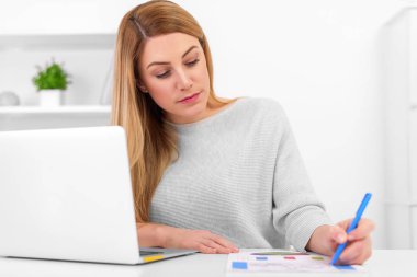 Dizüstü bilgisayar ile masada grafiklerle çalışma çekici genç bayan.