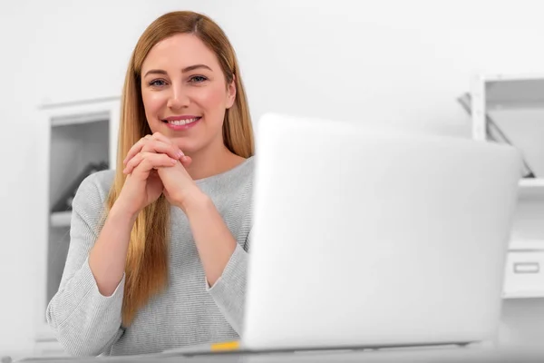 魅力的な女性は、自宅や職場で机に座っている間はカメラを見ています。ノート パソコン デスクの前に座って. — ストック写真