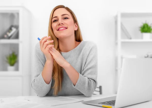 Blonde is thinking about a good or dreaming, sitting at the desk with a laptop. Office or work as a freelancer. — Stock Photo, Image