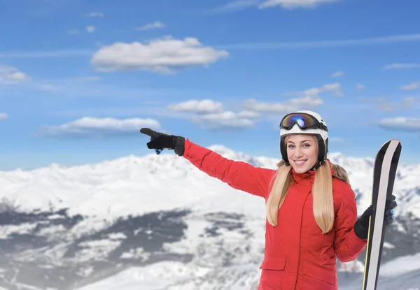 Skieur sur fond de montagnes enneigées. Jolie blonde en costume de ski rouge avec snowboard dans les mains spectacles sur les montagnes enneigées . — Photo