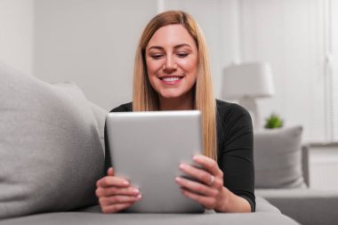 Çekici kadın evde kanepede yatan bir tablet PC'yi kullanma.