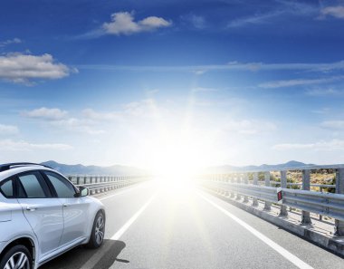 Güneş yüksek hızlı bir yolu boyunca acele bir beyaz araba.