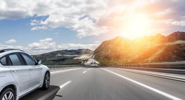 Güneş yüksek hızlı bir yolu boyunca acele bir beyaz araba.