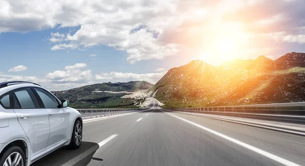 Un coche blanco corriendo a lo largo de una carretera de alta velocidad al sol . — Foto de Stock