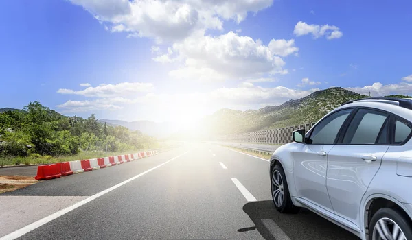 Un coche blanco corriendo a lo largo de una carretera de alta velocidad al sol . —  Fotos de Stock