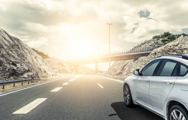 Een witte auto haasten langs een hoge snelheid weg in de zon. — Stockfoto