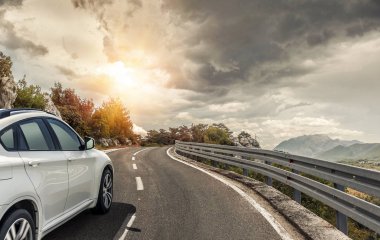 Güneş yüksek hızlı bir yolu boyunca acele bir beyaz araba.