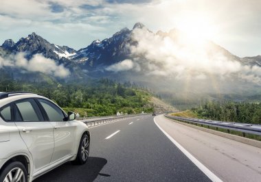 Güneş yüksek hızlı bir yolu boyunca acele bir beyaz araba.