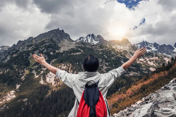 Tourist with hands up stands on the background of a mountain landscape. — Stock Photo, Image