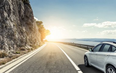 Güneş yüksek hızlı bir yolu boyunca acele bir beyaz araba.