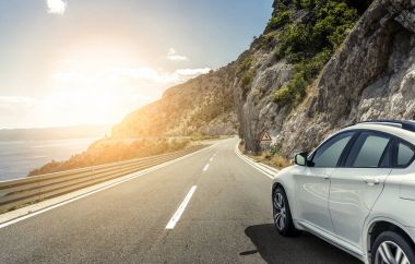 Güneş yüksek hızlı bir yolu boyunca acele bir beyaz araba.