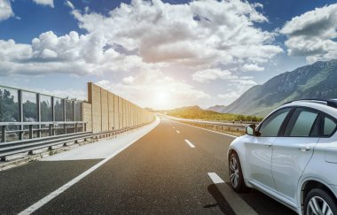 Güneş yüksek hızlı bir yolu boyunca acele bir beyaz araba.