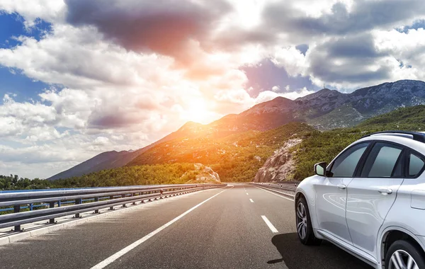 Bílé auto řítí po vysokorychlostní dálnici na slunci. — Stock fotografie