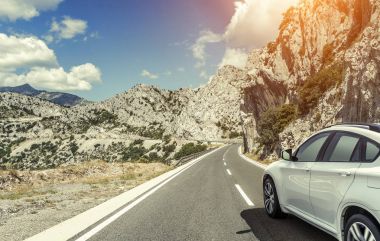 Güneş yüksek hızlı bir yolu boyunca acele bir beyaz araba.