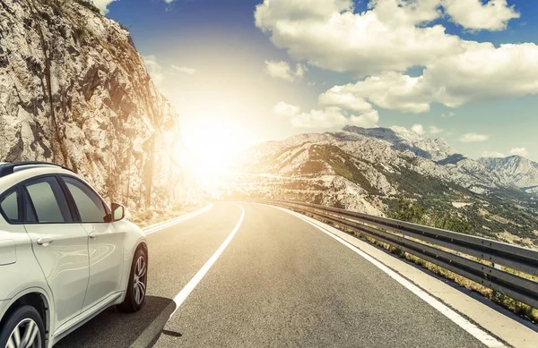 Um carro branco correndo ao longo de uma estrada de alta velocidade ao sol . — Fotografia de Stock