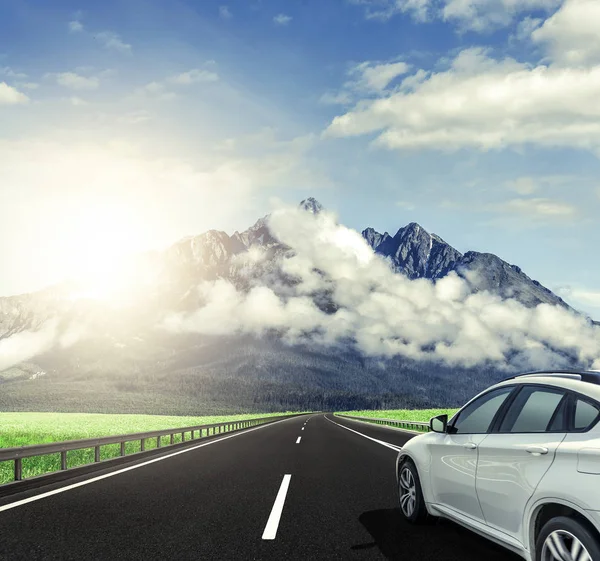 A white car rushing along a high-speed highway in the sun.