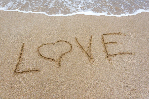 Das Wort Liebe im Sand am Strand. — Stockfoto