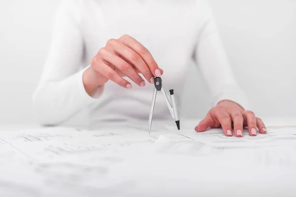 La mujer lleva en las manos la brújula, sobre la mesa con los dibujos . — Foto de Stock