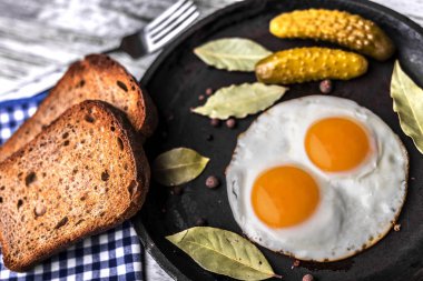 Bir tavada kızarmış yumurta. Çavdar tost ve kızarmış yumurta yanında salatalık turşusu.