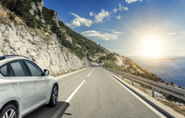Güneş yüksek hızlı bir yolu boyunca acele bir beyaz araba.