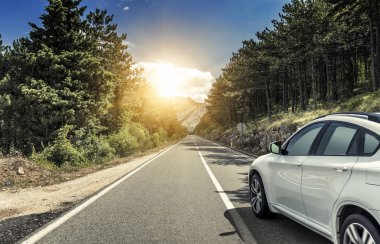 Güneş yüksek hızlı bir yolu boyunca acele bir beyaz araba.