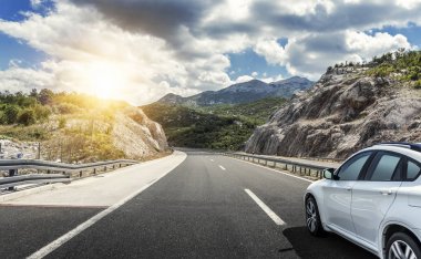 Güneş yüksek hızlı bir yolu boyunca acele bir beyaz araba.