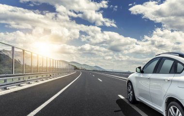 Güneş yüksek hızlı bir yolu boyunca acele bir beyaz araba.