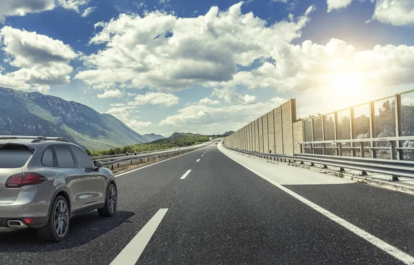 Coche corriendo a lo largo de una carretera de alta velocidad al sol . — Foto de Stock