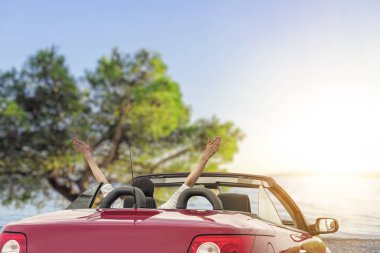 Deniz güneşli bir günde güzel dağlarının fonunda giden yolda arabadaki genç kadın.