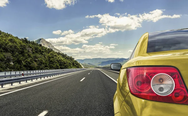 Żółty samochód pędzi wzdłuż autostrady szybkiego. — Zdjęcie stockowe