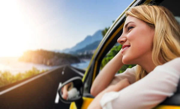 Reizen of vakantie. Mooi blond meisje in auto op de weg naar de zee. — Stockfoto