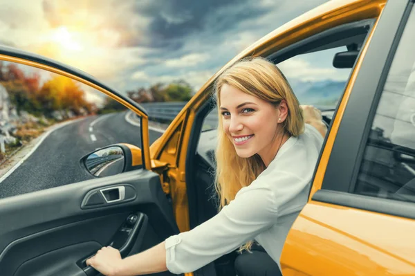 Krásná blond dívka řídit auto na dálnici. Pozvánka k cestování. Pronájem auta nebo dovolenou. — Stock fotografie