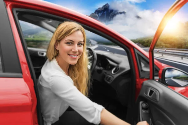 Hermosa chica rubia conduciendo un coche en la carretera. Invitación a viajar. Alquiler de coches o vacaciones . —  Fotos de Stock